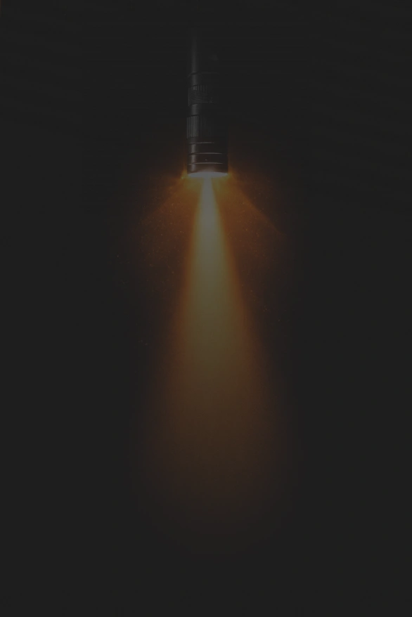 Black flashlight shining a bright orange beam downward against a dark background new